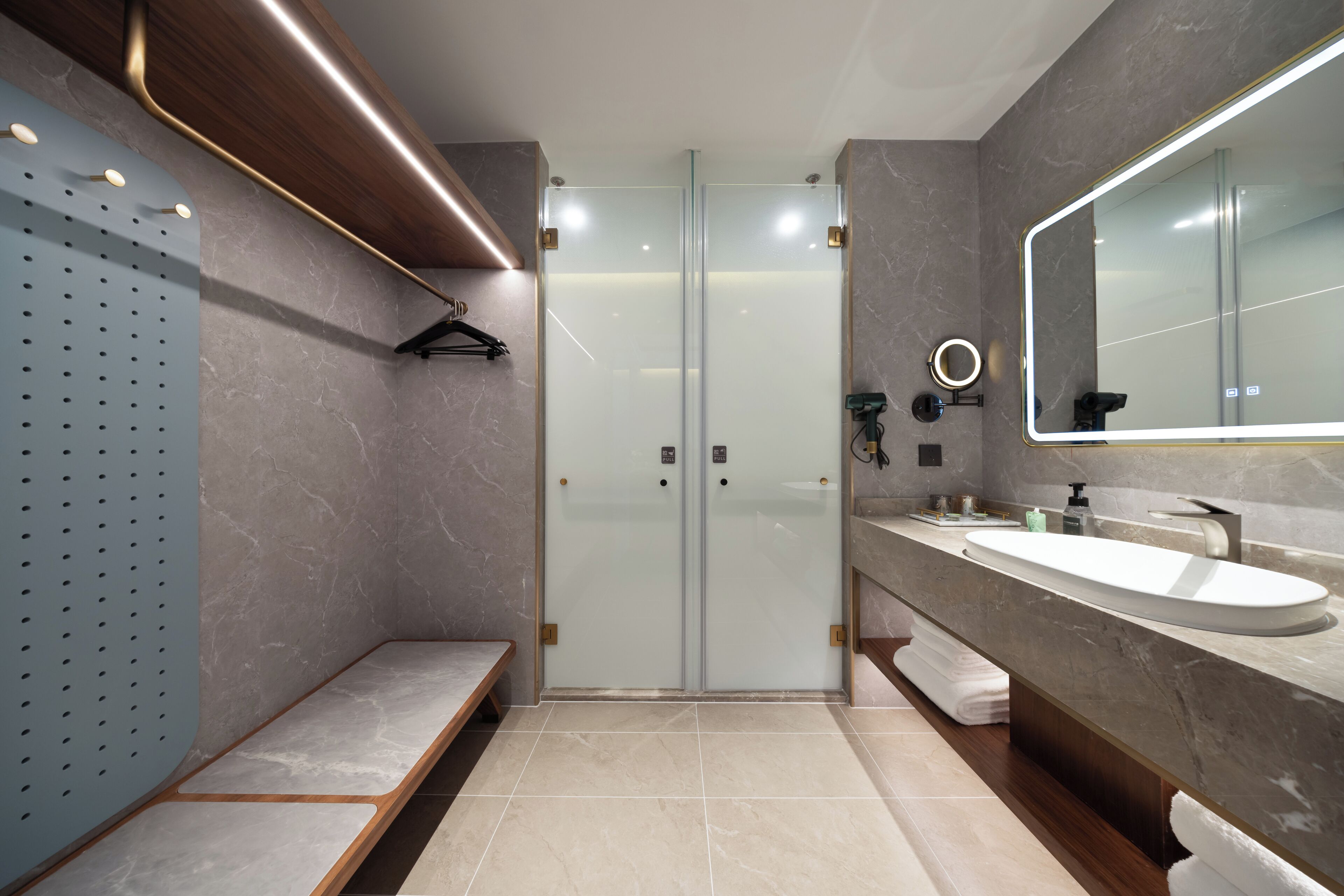 A modern bathroom with a glass shower enclosure, a large mirror, and a marble countertop.