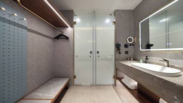 A modern bathroom with a glass shower enclosure, a large mirror, and a marble countertop.