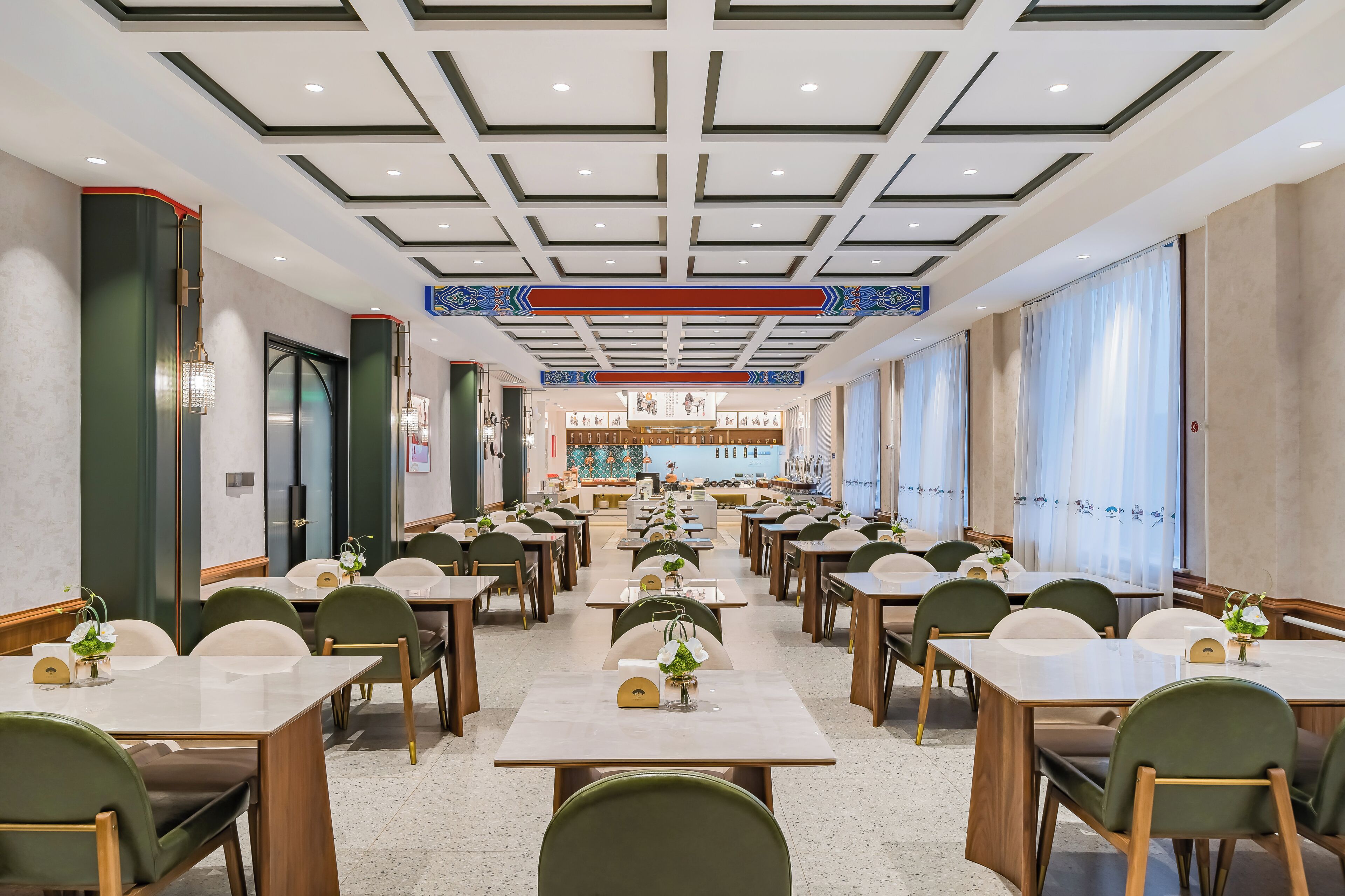 A spacious dining area with multiple tables and chairs, a central decorative wall, and a ceiling with geometric patterns.