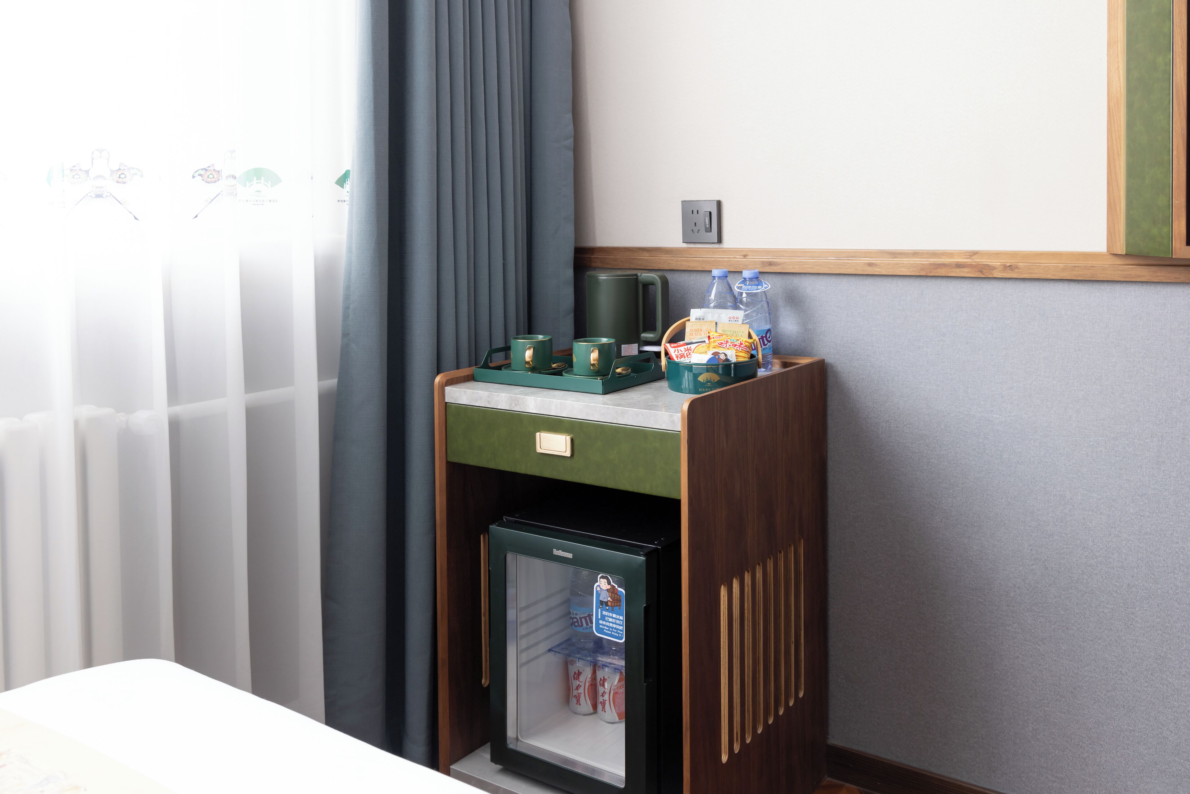 Una kitchenette compacta con refrigerador, cafetera y un mueble pequeño.