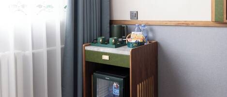 Una kitchenette compacta con refrigerador, cafetera y un mueble pequeño.