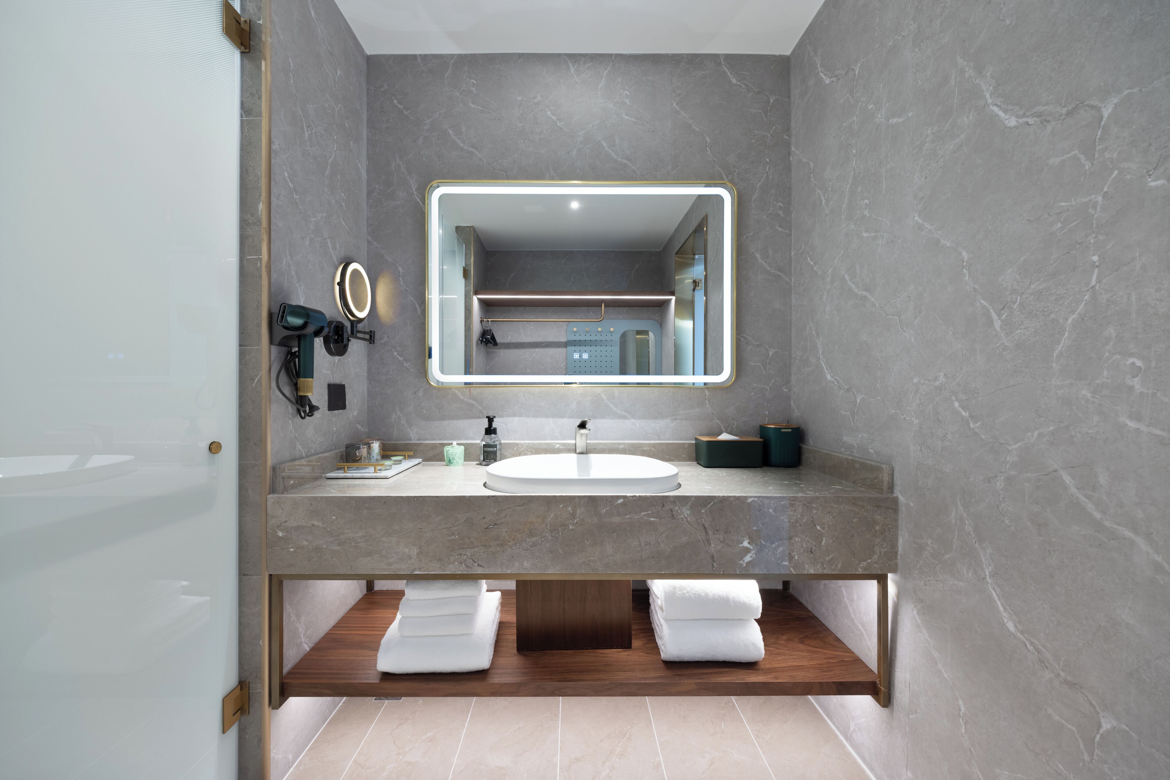 A modern bathroom with a marble vanity, a large mirror, and a built-in shower.