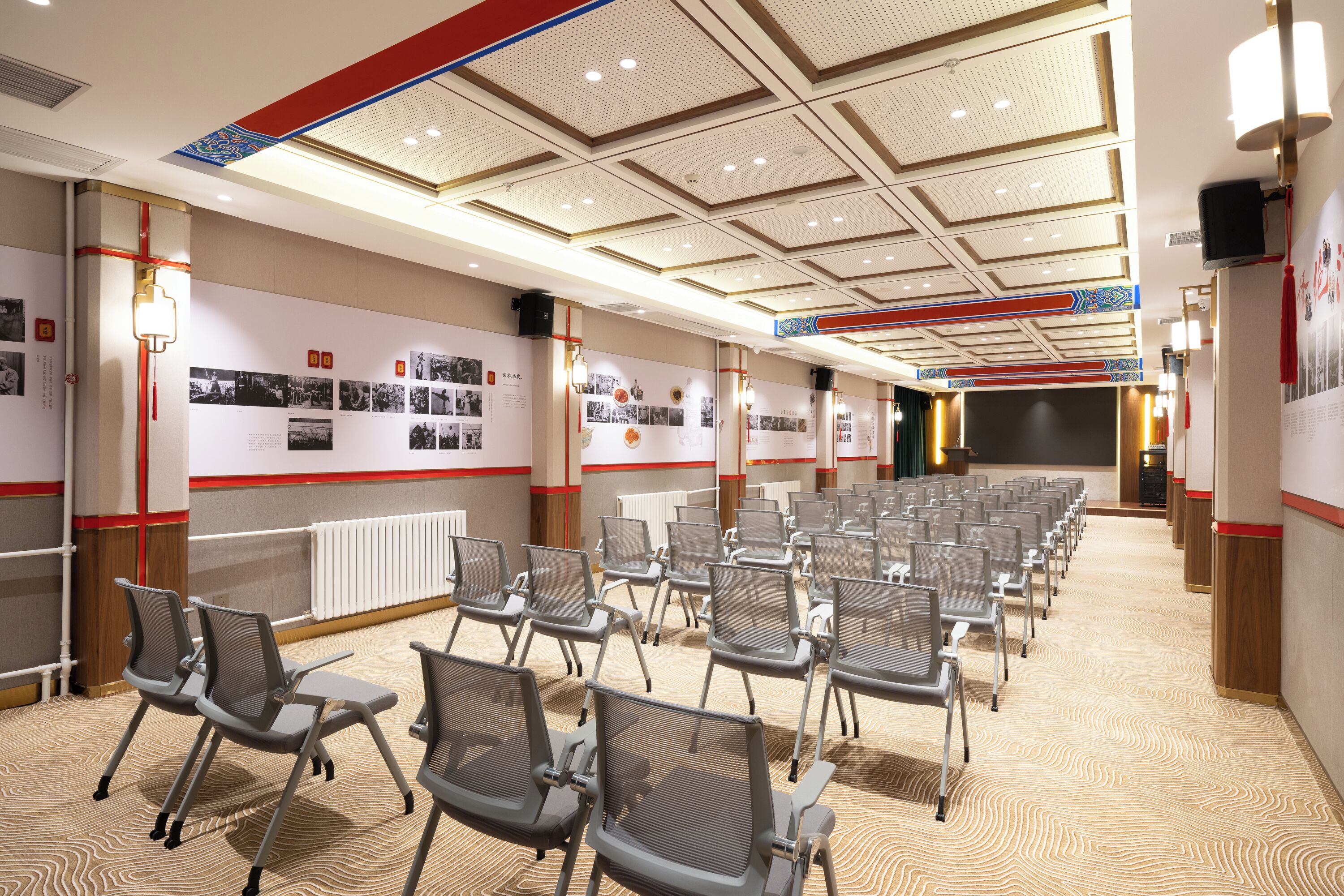 Une salle de conférence avec des rangées de chaises, une moquette à motifs et des affiches informatives accrochées aux murs.
