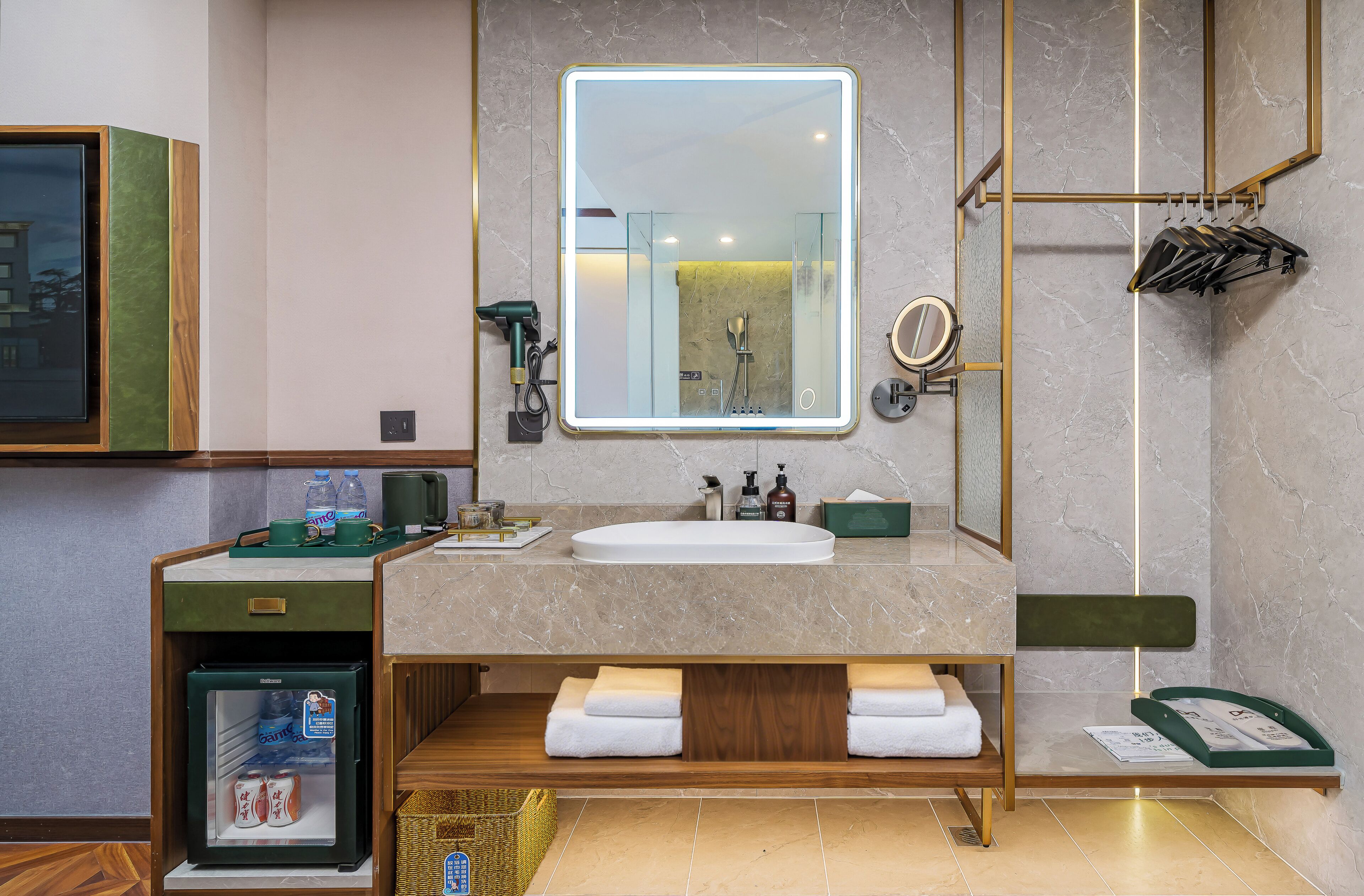 A modern bathroom with a marble sink, a large mirror, a towel rack, and a small refrigerator.