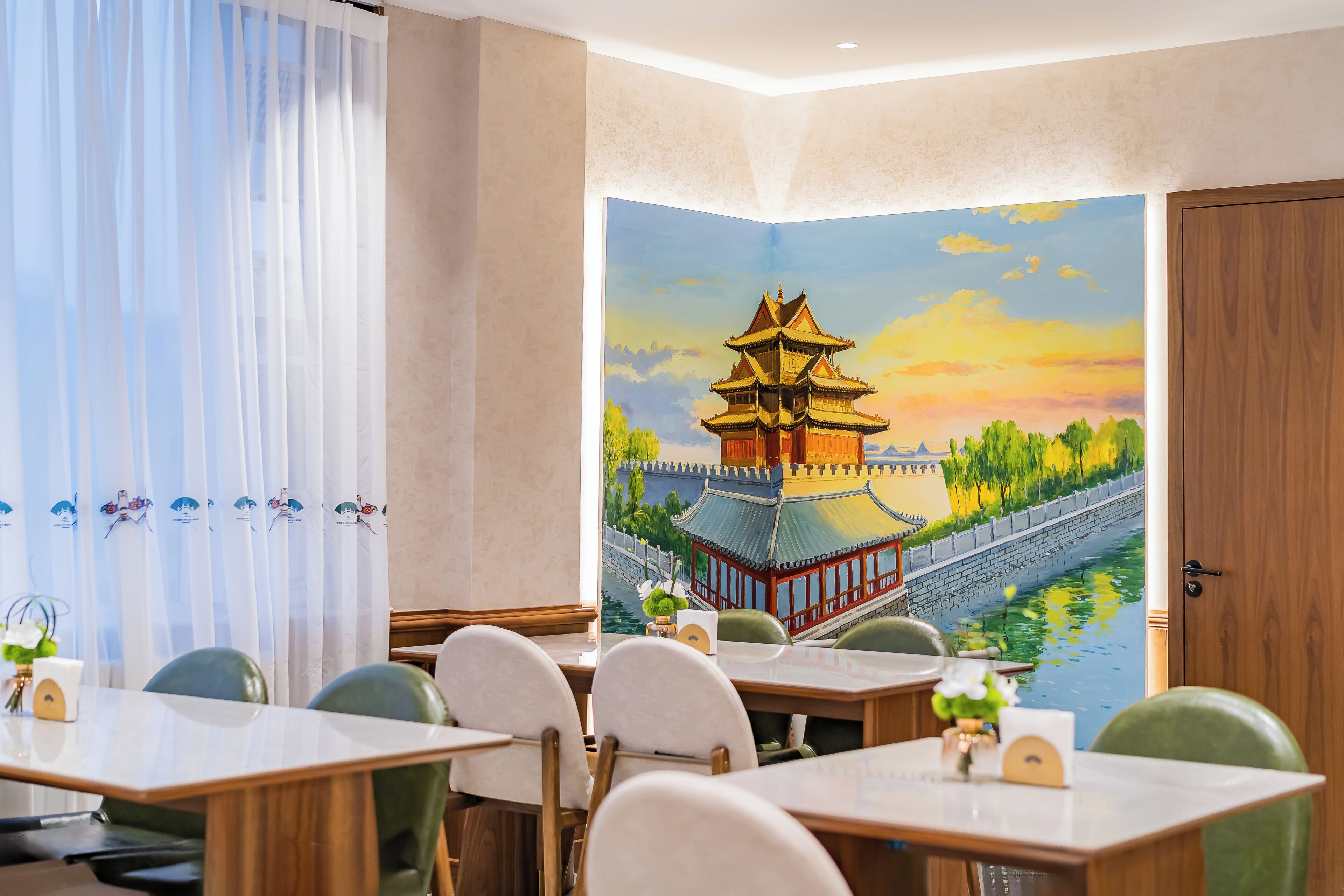 A dining area with tables and chairs, a mural of a pagoda, and a wooden door.