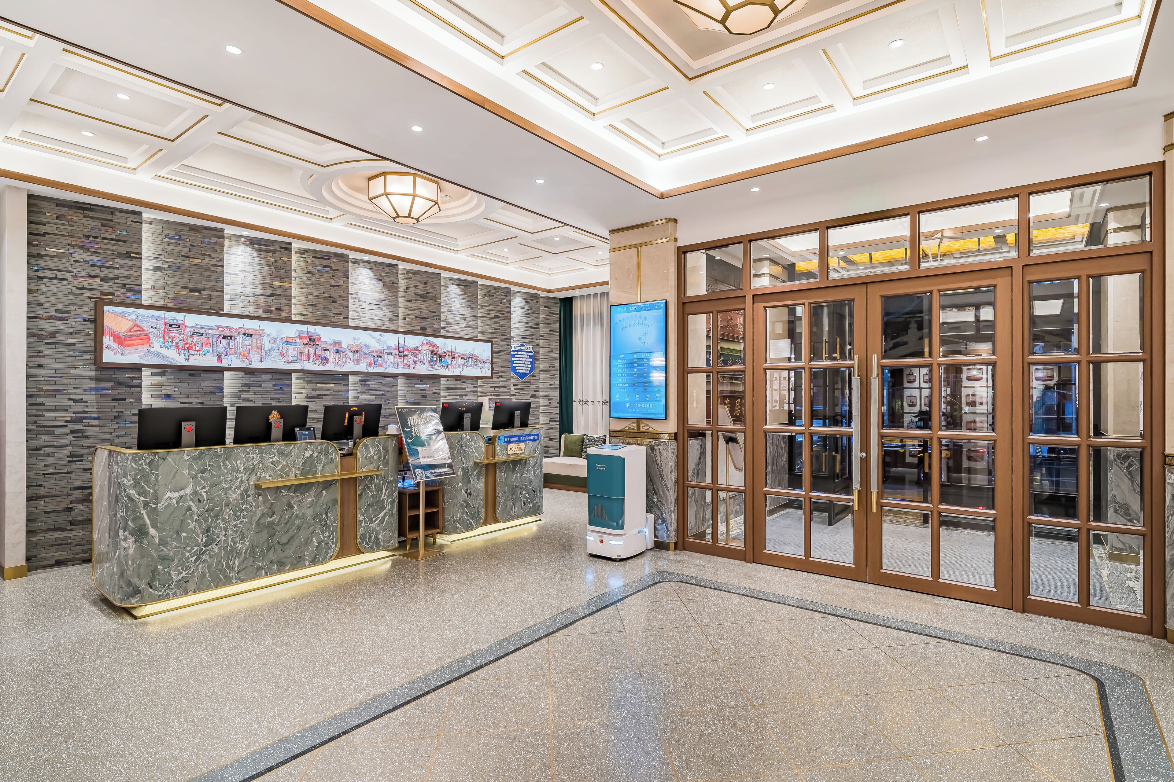A hotel reception area with a marble counter, a digital information board, and a glass door entrance.