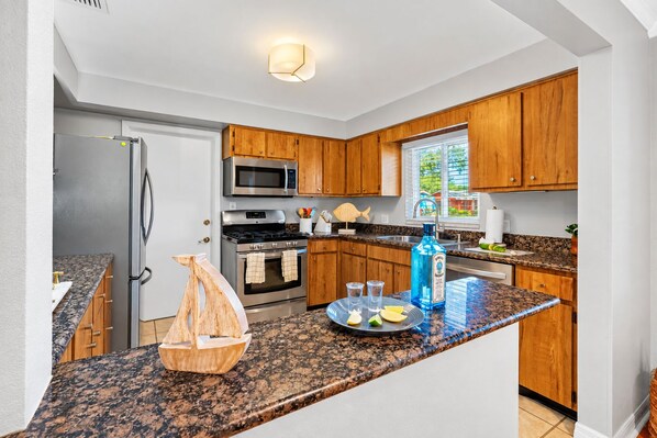 A modern kitchen with wooden cabinets, stainless steel appliances, and a granite countertop.
