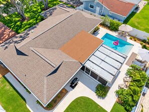 Una propiedad residencial con piscina, terraza techada y césped bien cuidado.