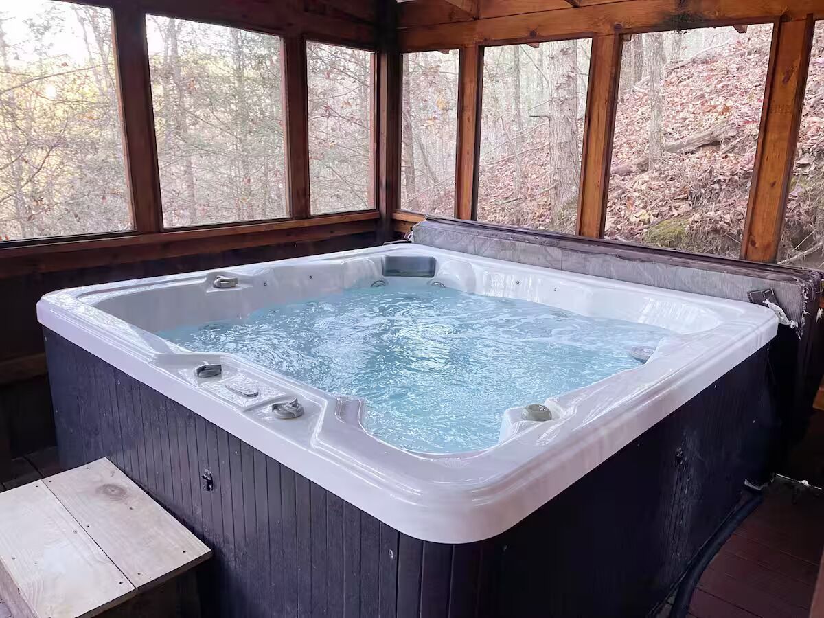 Un jacuzzi en una cabaña de madera con vistas a los árboles.