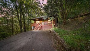 A cabin with a wooden deck and stairs leading to the entrance. - Cozy Cabin w/ Hot Tub – Sleeps 8 Comfortably (Pigeon Forge)