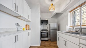 A modern kitchen with white cabinetry, stainless steel appliances, and a wooden floor. - Updated Studio in Downtown Long Beach - Walk to Everything (Long Beach)