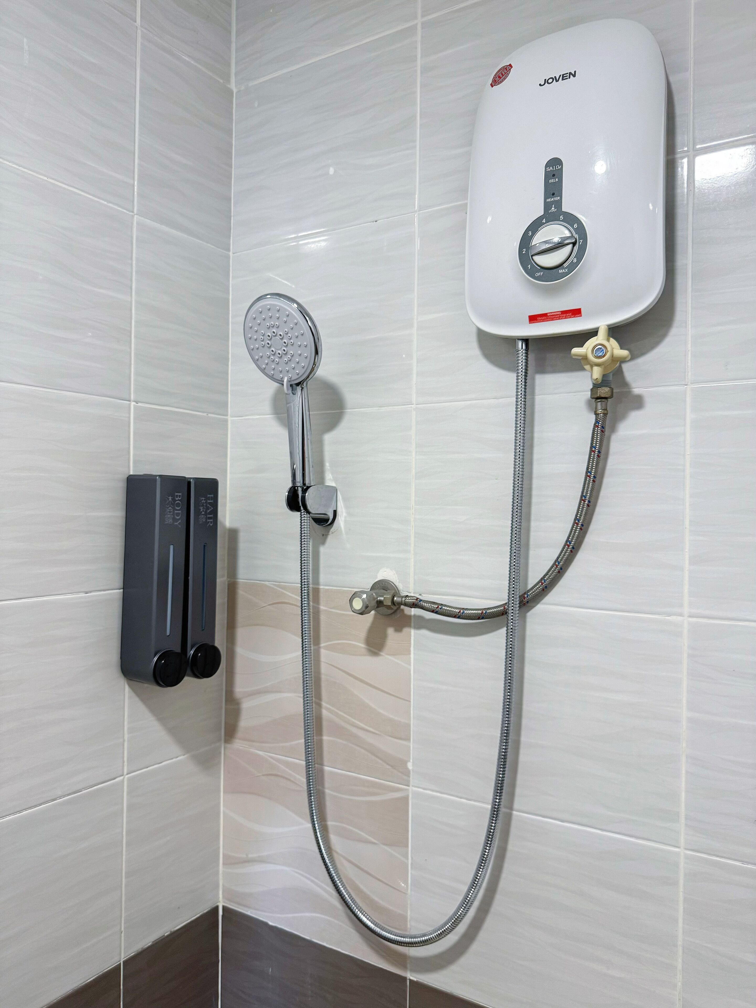 A shower with a handheld showerhead and a wall-mounted control panel.
