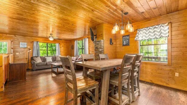 L’intérieur d’un chalet en bois, avec une table à manger, des chaises, un canapé et une cheminée.