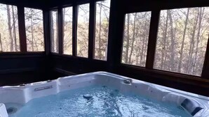 Un bain à remous avec vue sur une forêt, grâce à de grandes fenêtres.
