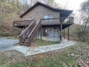 Una cabaña de madera con fachada de piedra, una escalera de madera y una terraza.
