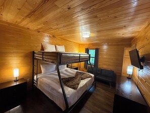 Habitación con literas, paredes de madera y un escritorio con silla.