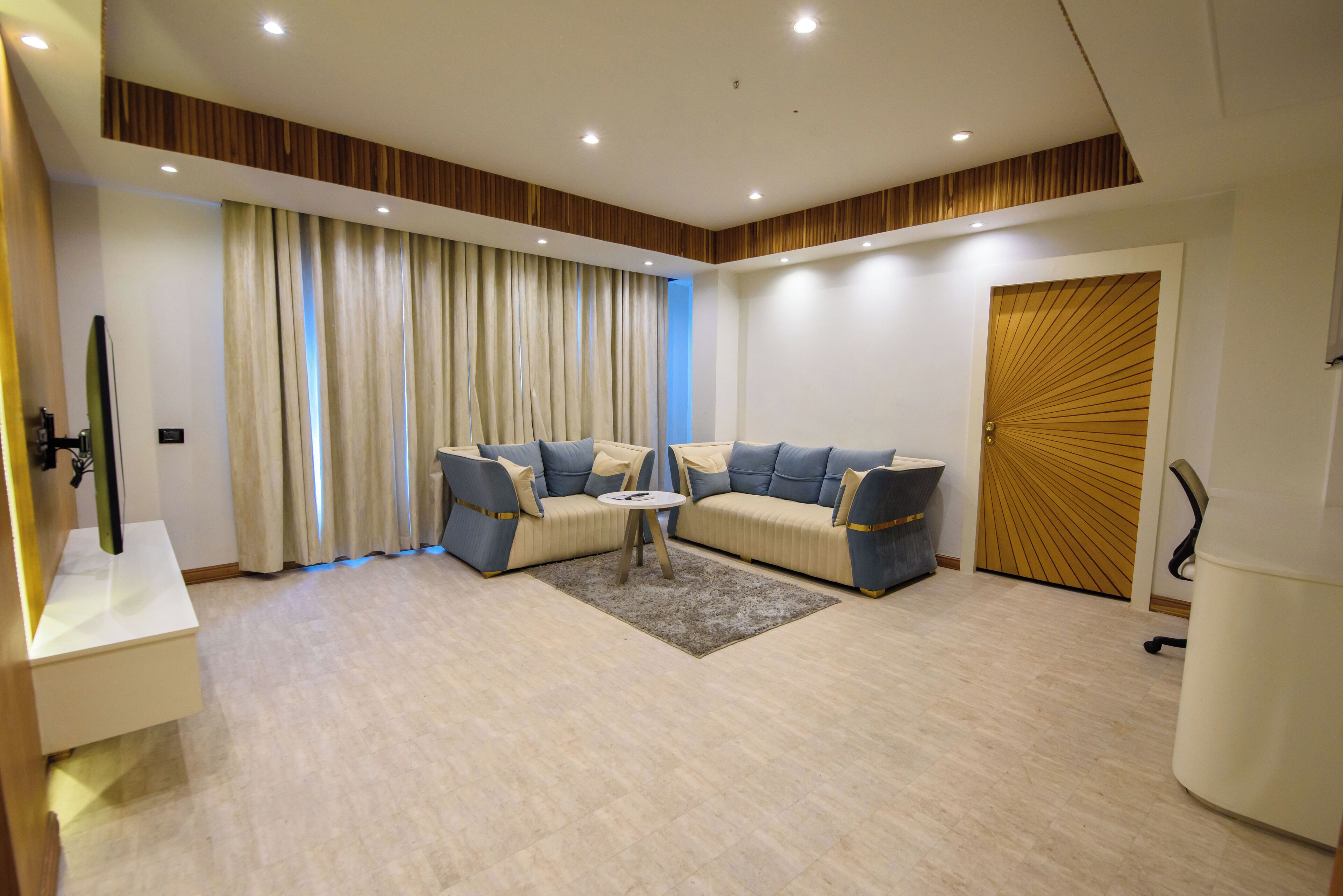 A modern living room with a sofa set, a coffee table, and a large window with curtains.