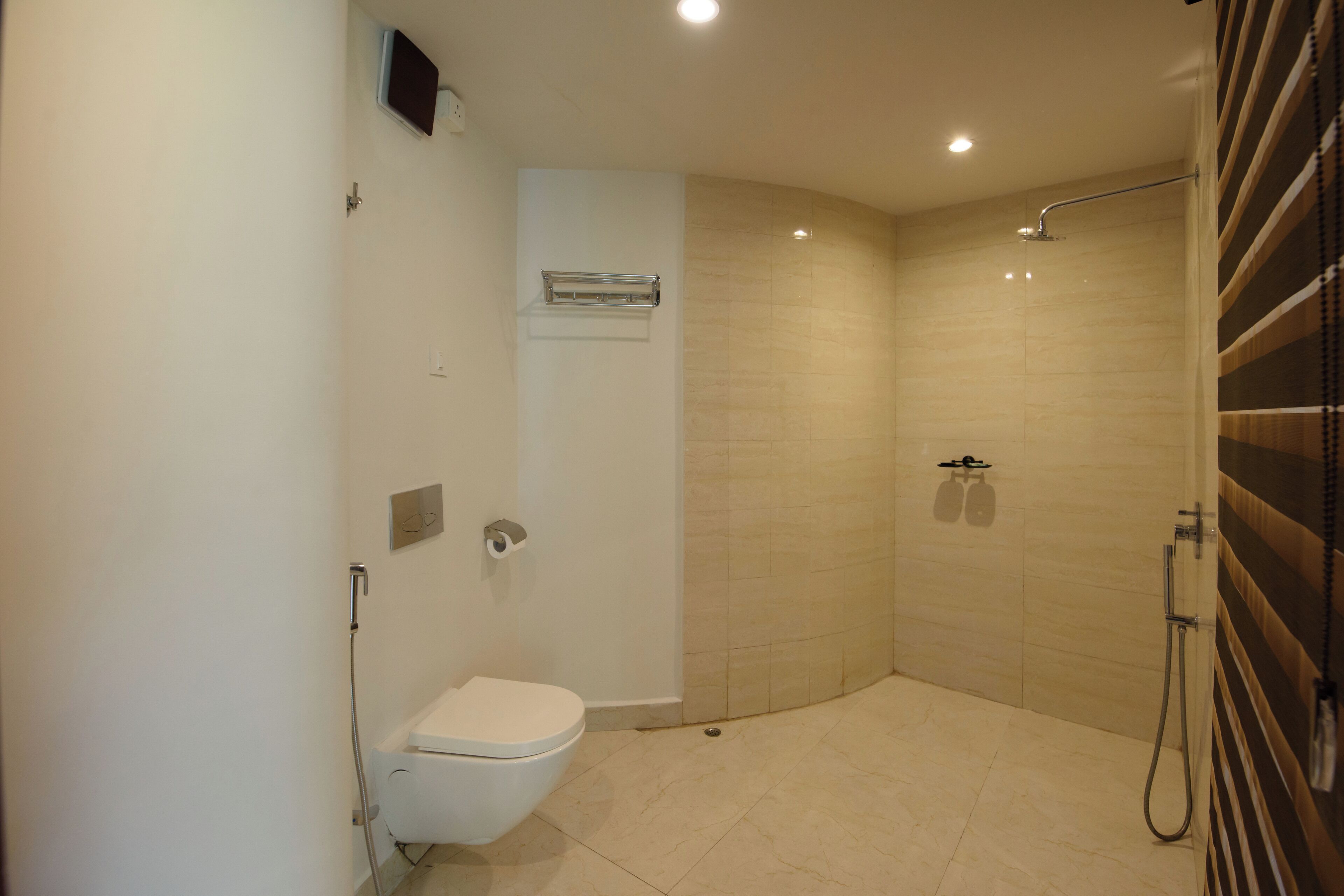 Uma casa de banho moderna com sanita, chuveiro e um porta-toalhas.