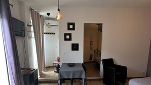 Ein moderner, gut beleuchteter Raum mit einem Esstisch, Stühlen, einer Couch und einem Bett.