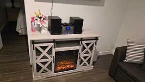 Un salon avec une cheminée, un téléviseur fixé au mur et un canapé agrémenté d’un coussin à rayures.