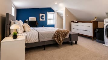 A bedroom with a bed, bedside table, lamp, and a dresser.