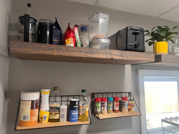 Two wooden shelves with kitchen items, a coffee machine, and a potted plant.