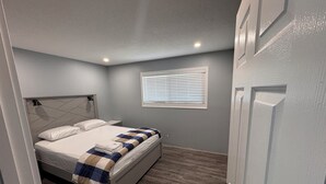 Ein Schlafzimmer mit einem Bett, einem Fenster mit Jalousien und einer Tür.