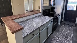 A modern kitchen with a granite countertop, white cabinets, and a black stove.