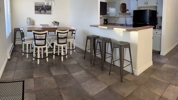 A modern kitchen with a central island, bar stools, and a dining area with chairs.