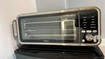 A Ninja toaster oven with a digital control panel, placed on a black appliance.