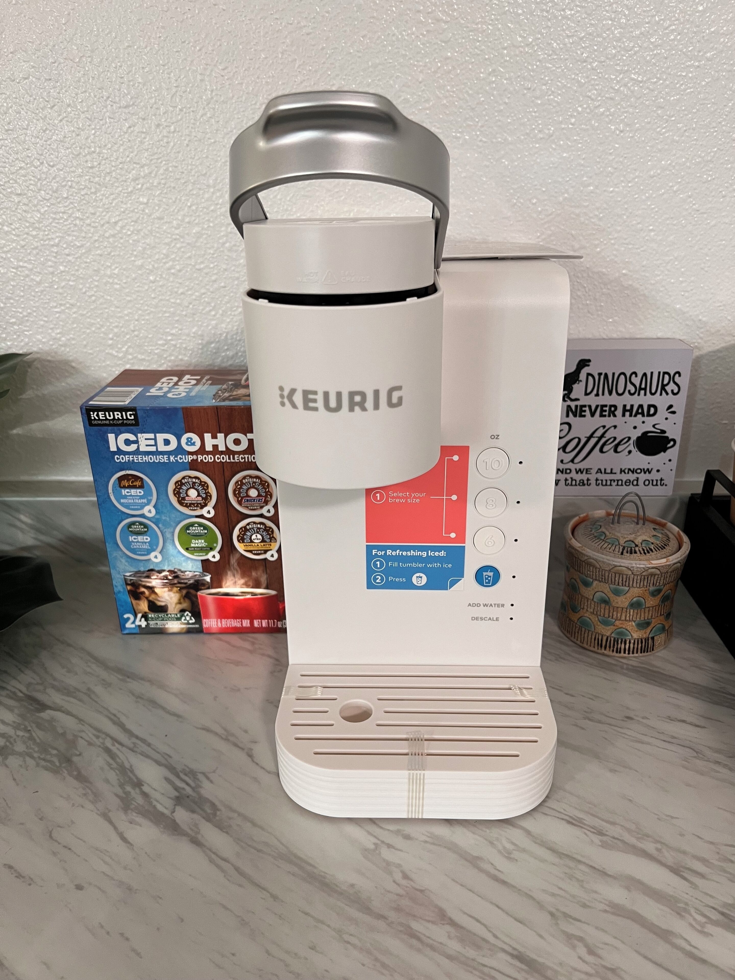 A Keurig coffee maker with a pod collection box beside it.