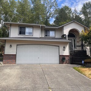 A two-story house with a garage, a brick foundation, and a number 7915 on the front wall.