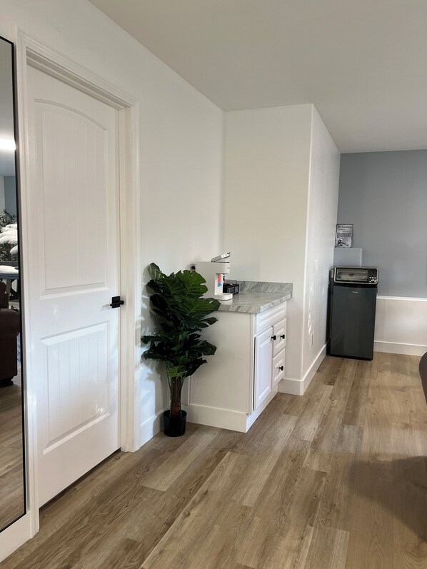 A modern kitchen with white cabinetry, a countertop, a sink, a refrigerator, and a potted plant.