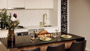Una cocina moderna con una isla central, sillas negras y un jarrón decorativo con flores.