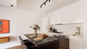 Una cocina moderna con armarios blancos, encimera negra y lavavajillas integrado.