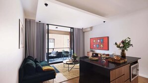 Una sala de estar moderna con un sofá, una mesa de centro y una zona de cocina con encimera y armarios.