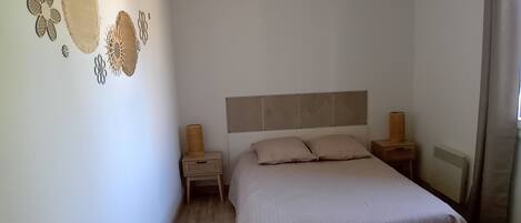 Une chambre à coucher comprenant un lit, des tables de chevet, un luminaire fixé au mur et des éléments décoratifs sur les murs.