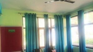 Una habitación con dos sillas, un ventilador de techo y una ventana con cortinas.