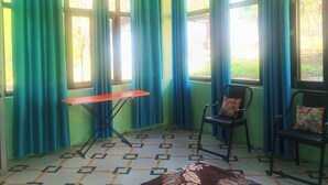 Una habitación con una mesa, dos sillas y ventanas amplias con cortinas.