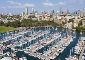 Un port de plaisance rempli de nombreux bateaux amarrés dans une baie, avec la silhouette d’une ville en arrière-plan.