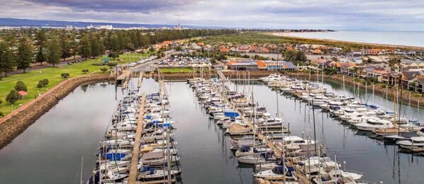 A marina with numerous boats docked in a calm water setting, surrounded by a residential area with houses and greenery.