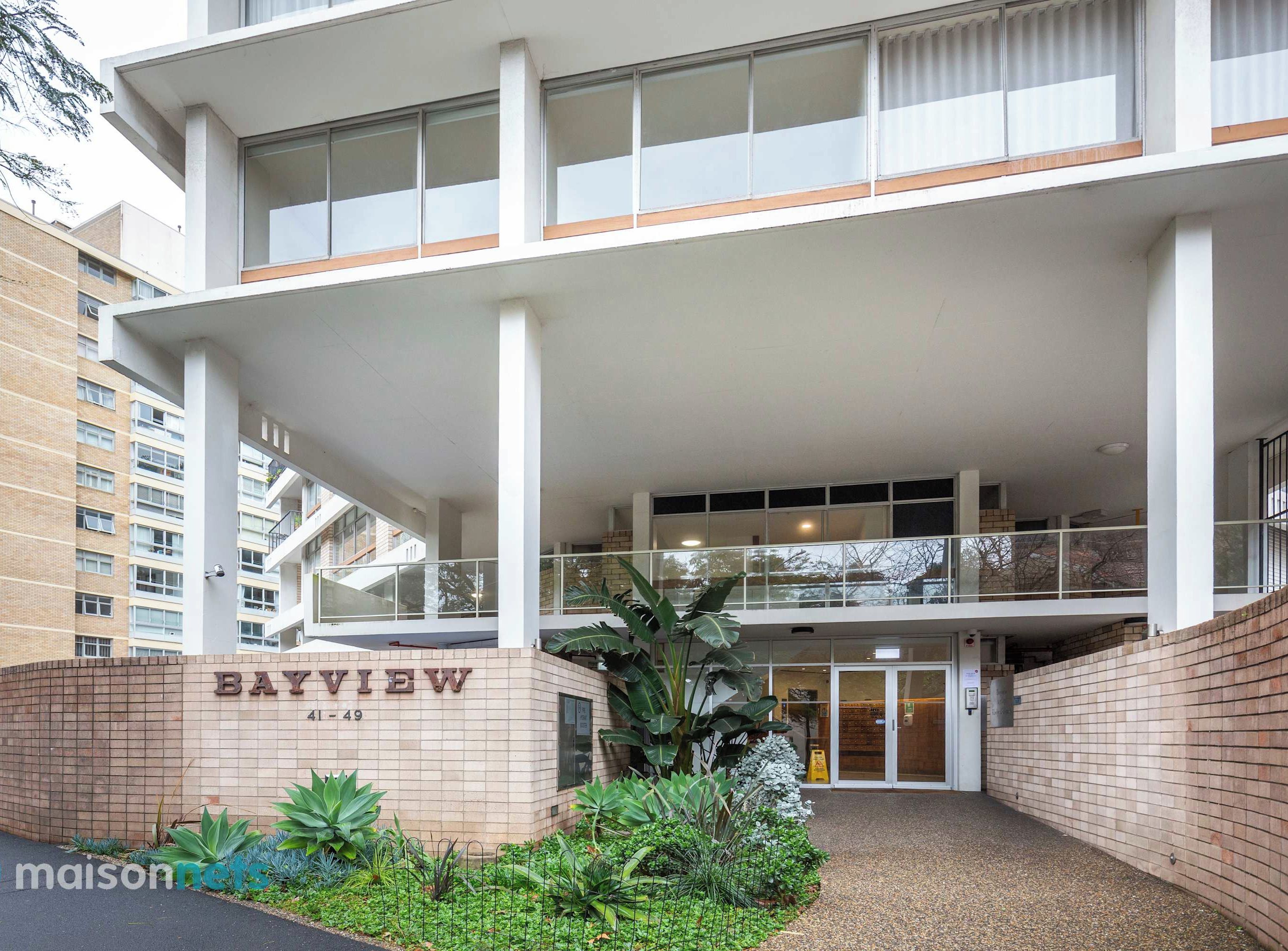 Un edificio moderno con un letrero que dice 'Bay View' y una entrada protegida por una reja.