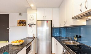 Une cuisine moderne dotée d’un réfrigérateur en acier inoxydable, d’un évier à deux bacs et d’une plaque de cuisson noire.