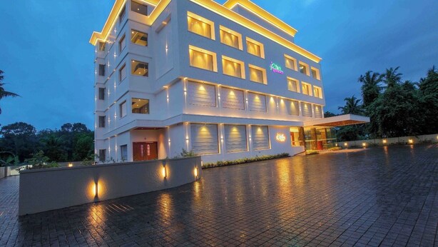 A multi-story hotel with a modern design, featuring a prominent entrance with a covered area and a well-lit facade. - Park Residency Puthupally (Kottayam)