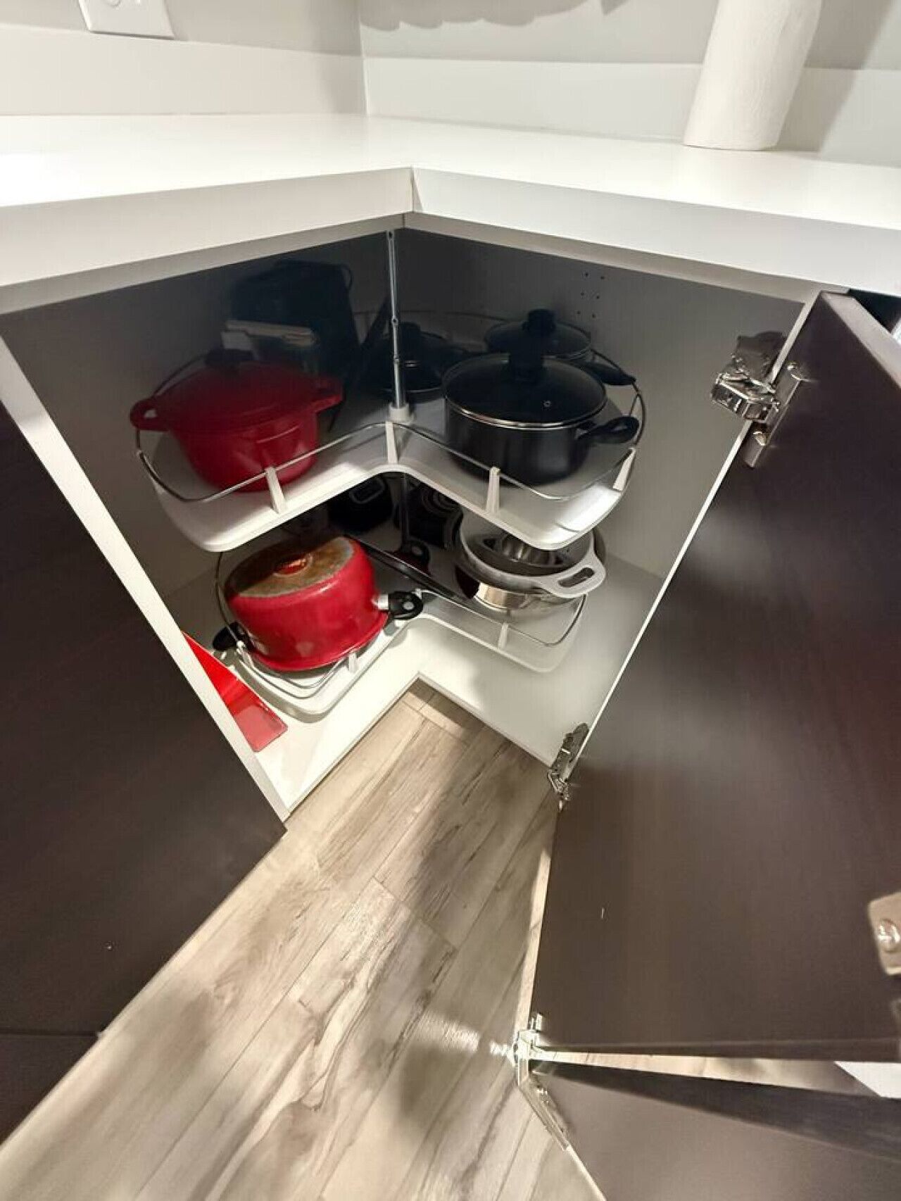 A compact kitchen with a stove, a red pot, and a black pot on the stove.
