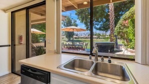 A kitchen with a large window, a dishwasher, and a sink. - Golf View Retreat w/ Sunset Patio, Media Room, Fireplace & Pool/Spa Steps Away (Palm Desert)