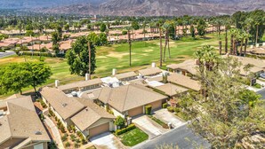 A residential area with single-family homes, a well-maintained lawn, and a mountain backdrop. - Golf View Retreat w/ Sunset Patio, Media Room, Fireplace & Pool/Spa Steps Away (Palm Desert)