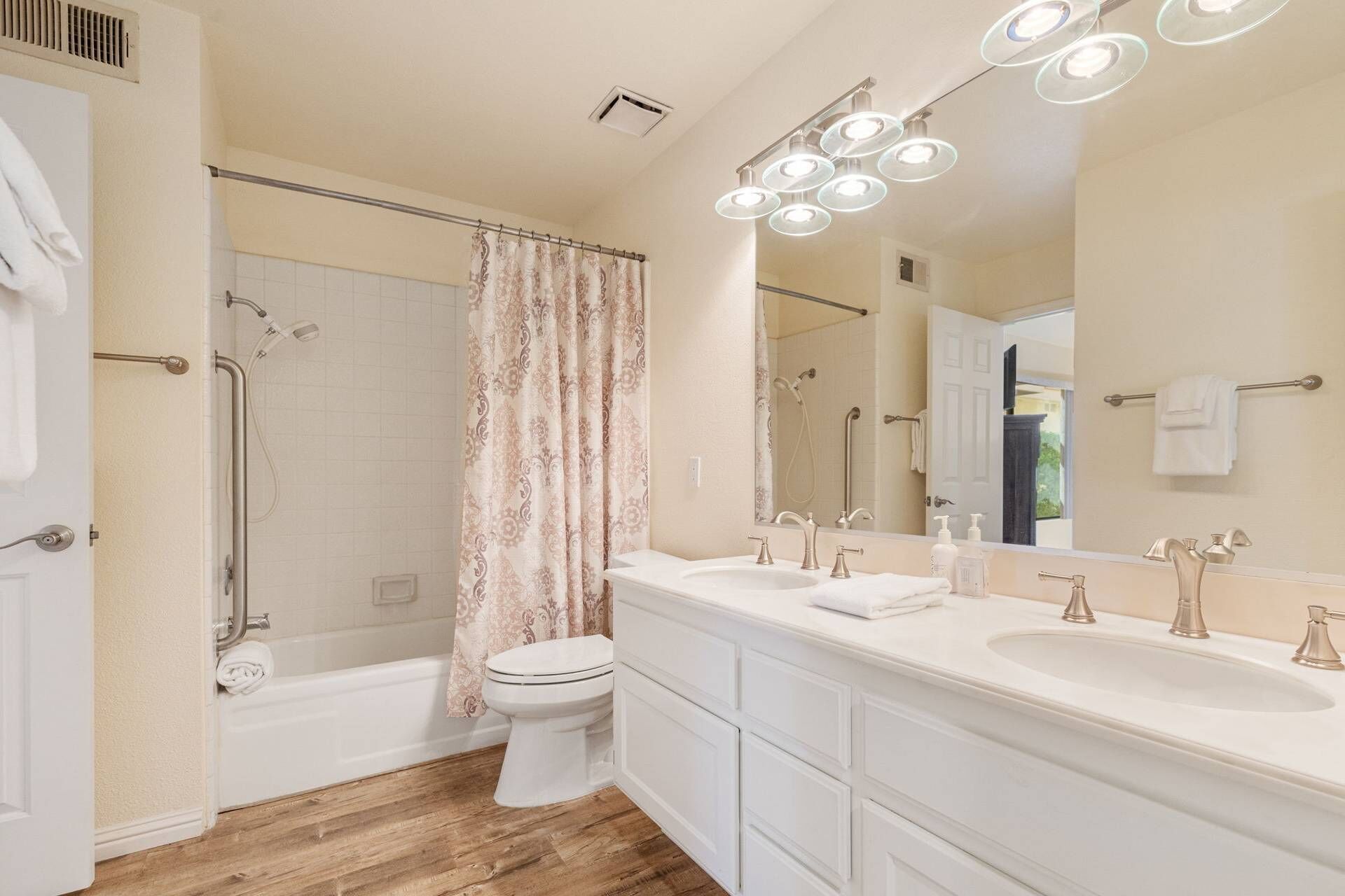 Une salle de bain avec douche, toilettes et un meuble-lavabo double doté d’un grand miroir.