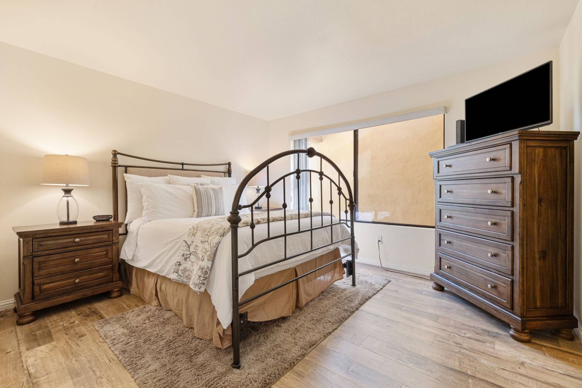 Un dormitorio con cama, mesita de noche, cómoda y televisor.