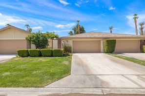 A residential house with a garage, a well-maintained lawn, and a clear sky. - Golf View Retreat w/ Sunset Patio, Media Room, Fireplace & Pool/Spa Steps Away (Palm Desert)